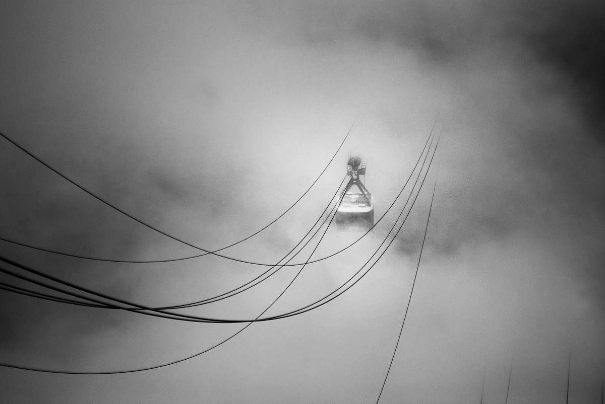 black-and-white grayscale photo of cable car in the midst of clouds grey